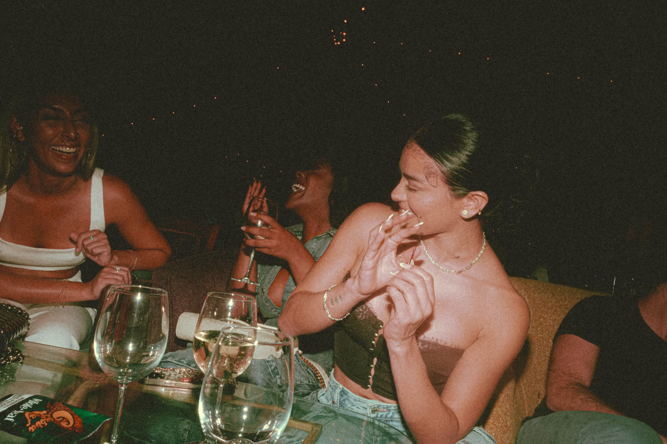 Friends gathered around a candlelit table with wine, mid-conversation